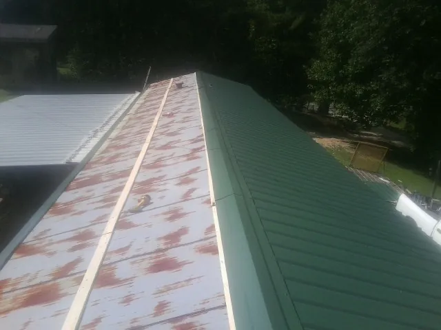 Old rusted panels beside newly installed green metal roofing — Wind Damage Roof Repair by Roofing Brothers in Maugansville