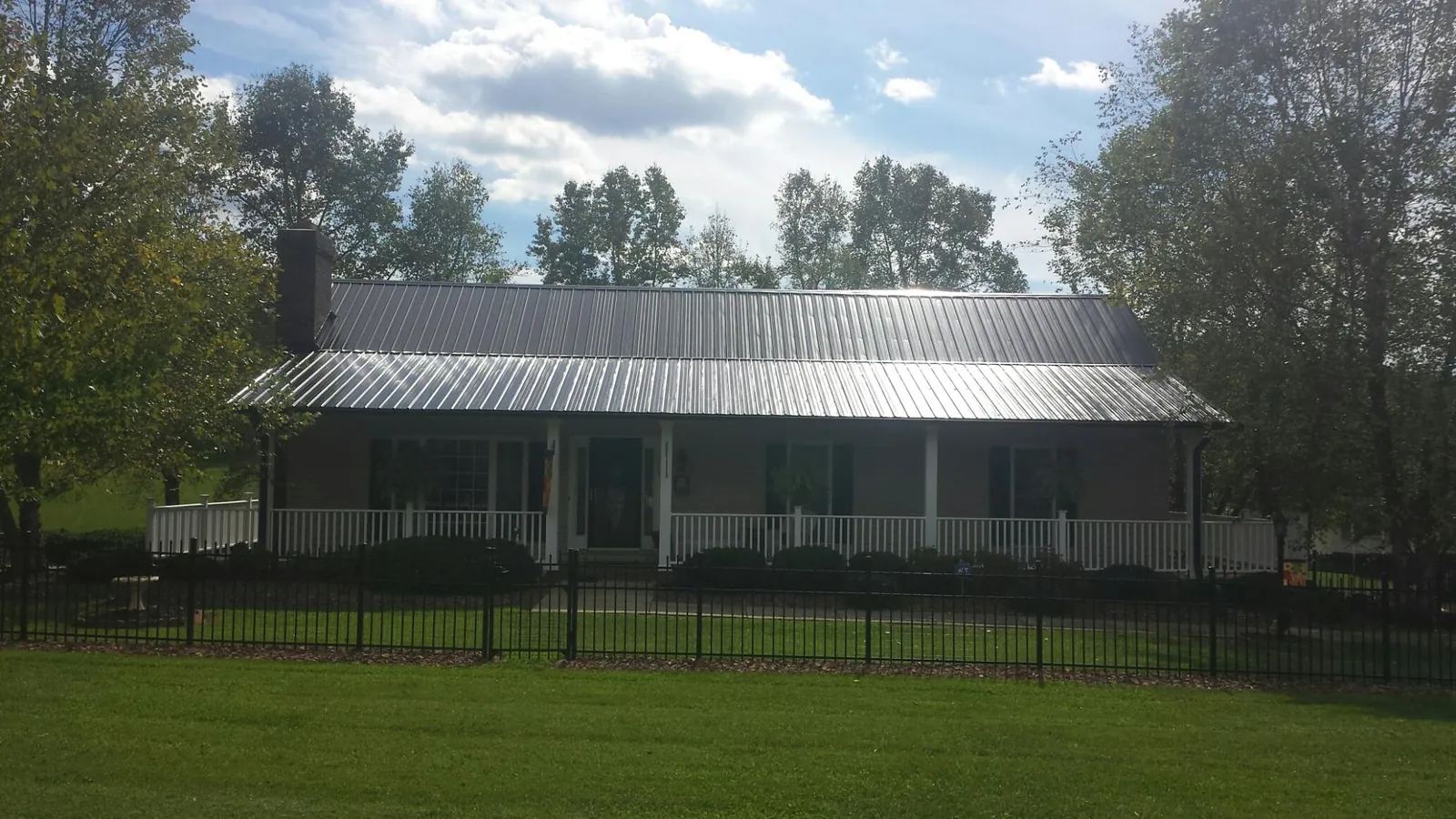 Gray metal roof on a brick ranch with a full width front porch — Gutter Guard Installation work by our crew in Maugansville