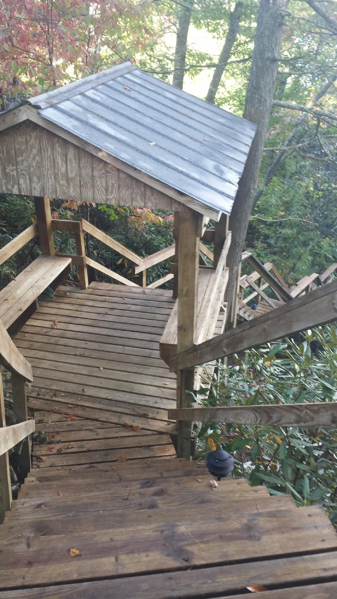 Metal roofed shelter over wooden steps on a wooded walkway — Skylight Repair & Installation work by our crew in Maugansville