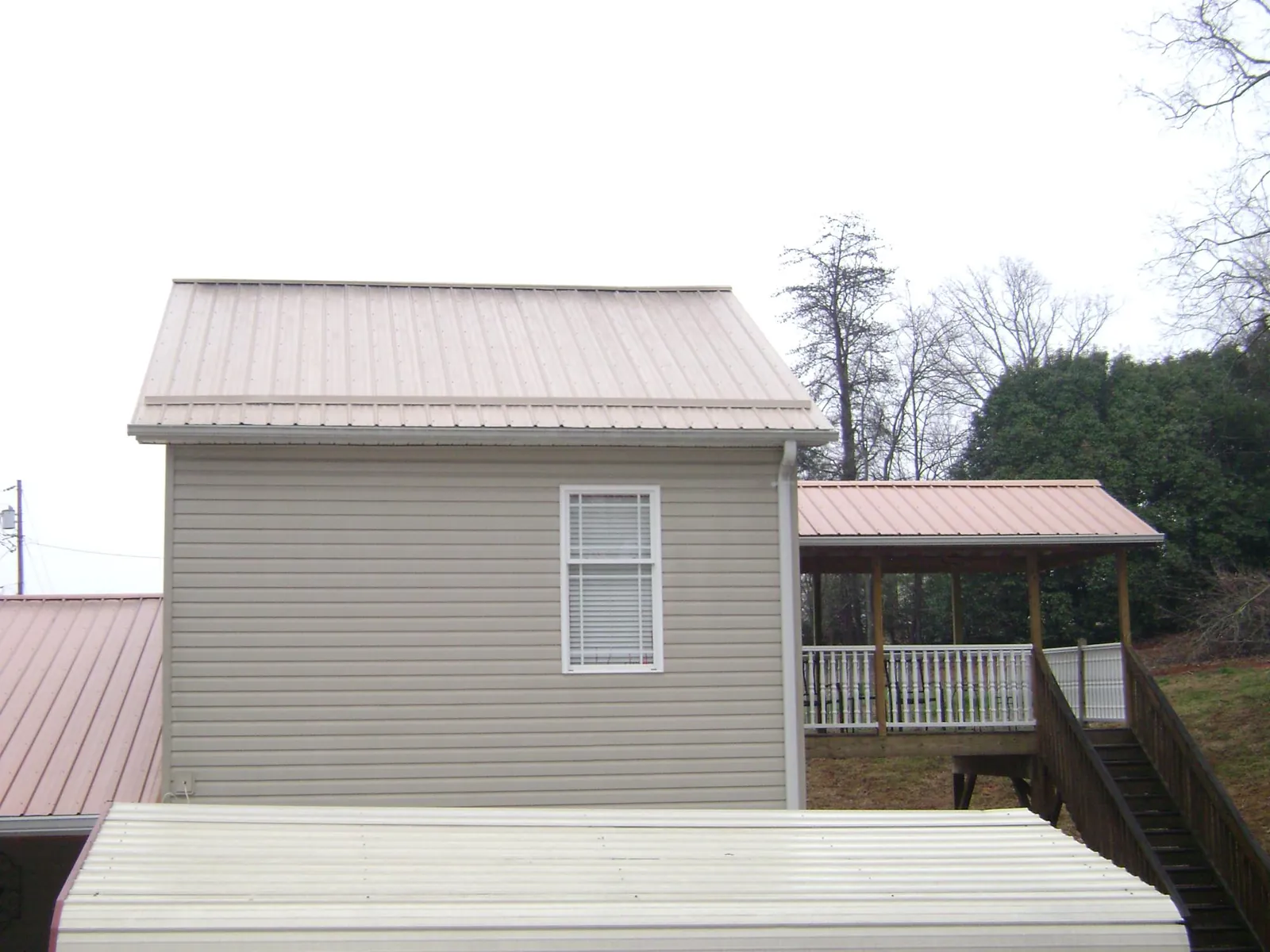 Tan metal roofs on a two story addition and attached porch, from a Roof Replacement job in Maugansville