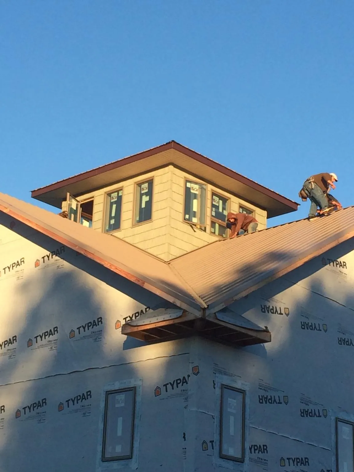 Roofers working around a rooftop cupola on a new metal roof at sunset — Roof Waterproofing in Maugansville by Roofing Brothers